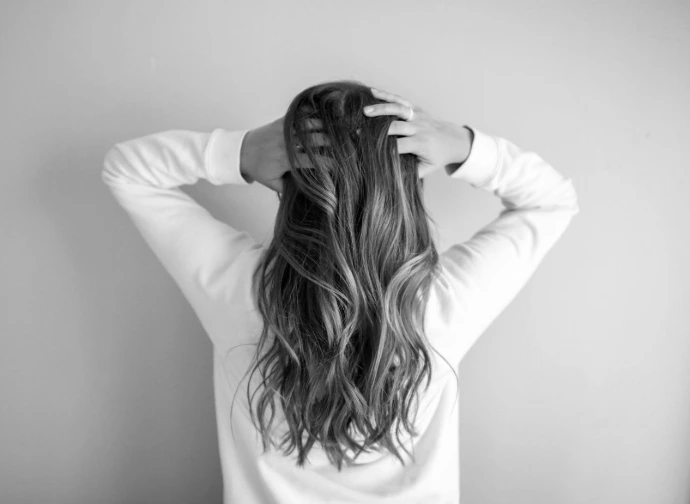 woman in white long-sleeved shirt standing in front of pink wall